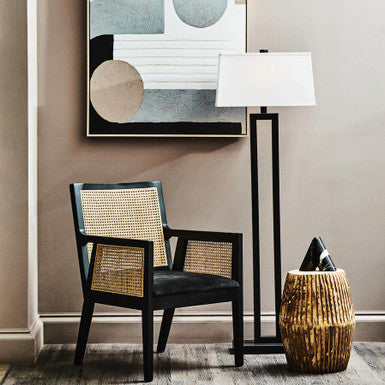 Orsina Arm Chair in black and natural rattan with modern decor and floor lamp