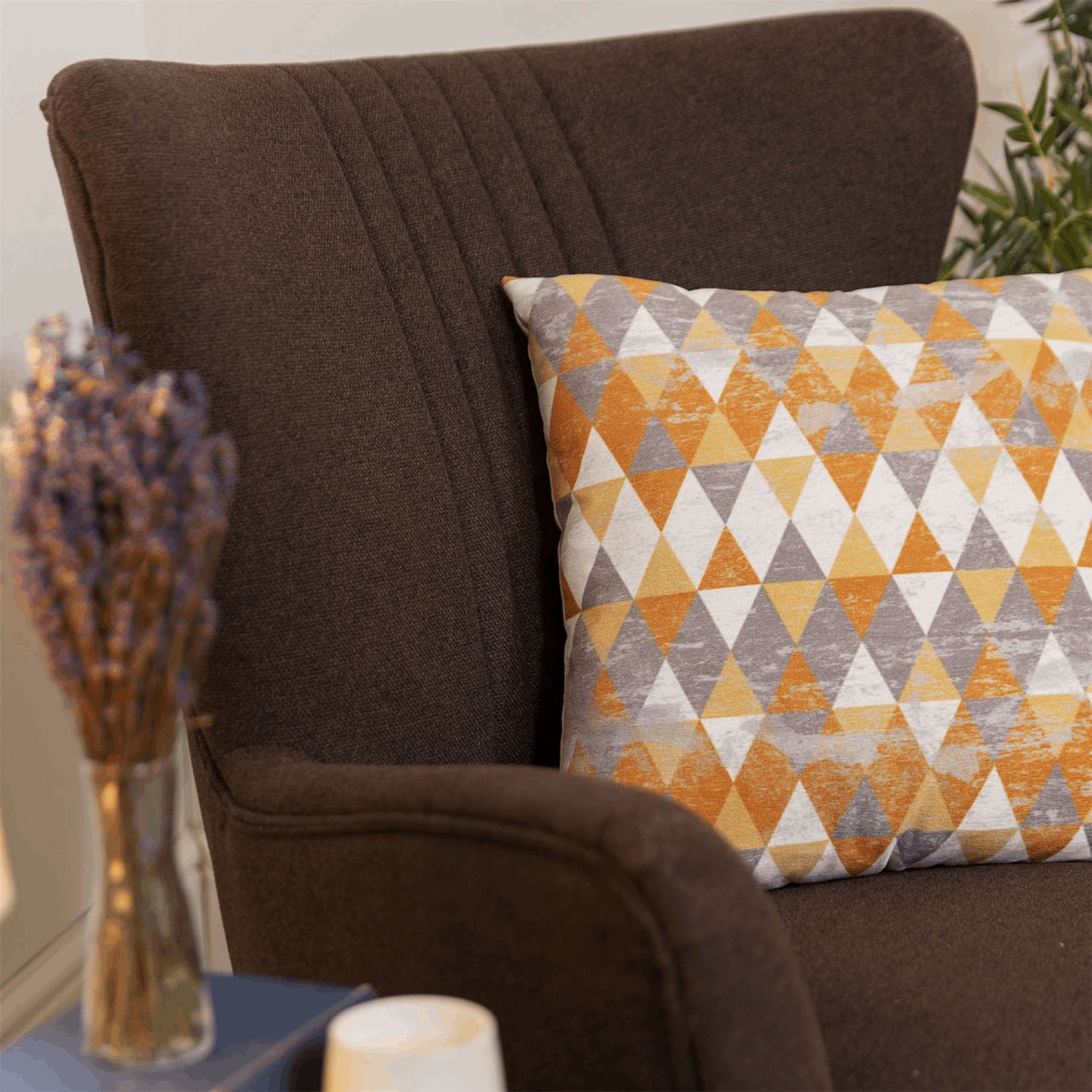 Widdop armchair in brown fabric with a colourful geometric patterned cushion