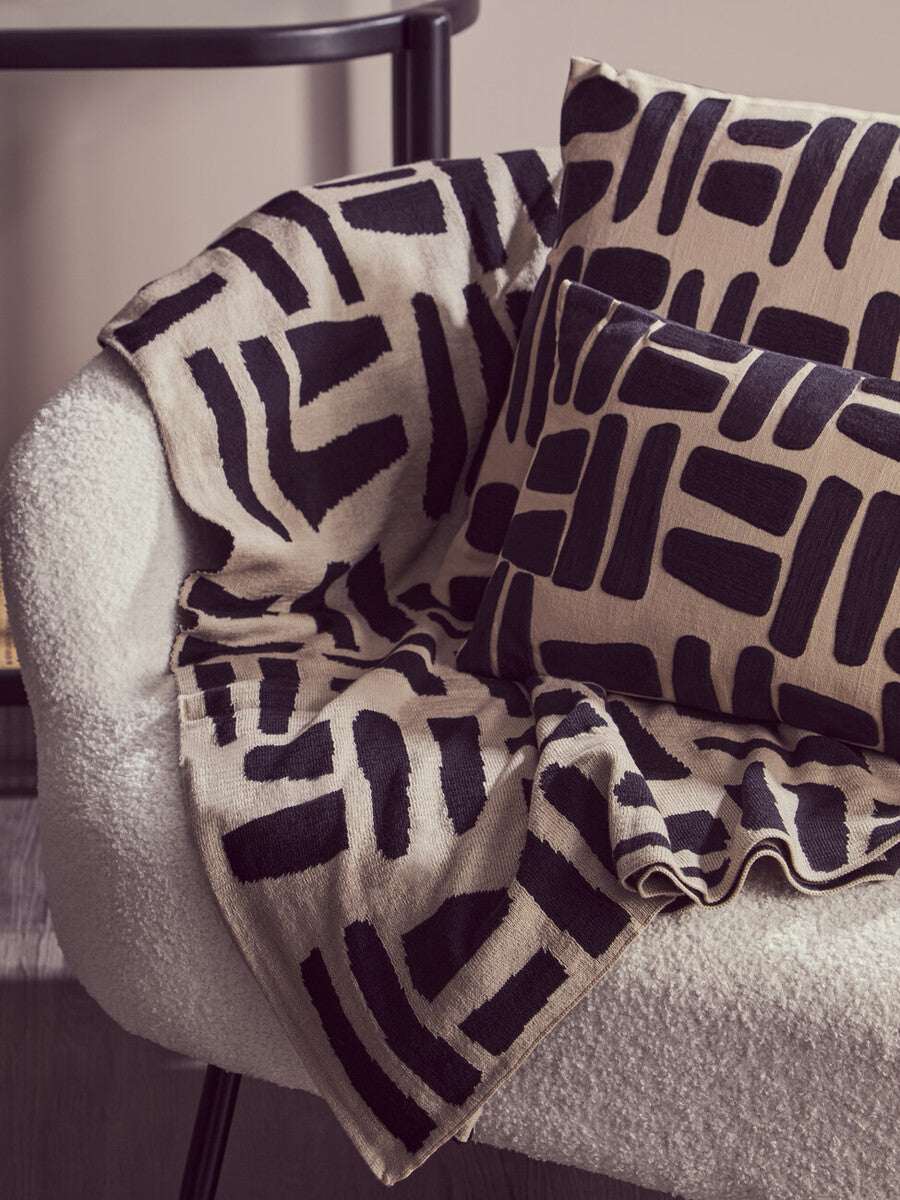 Orsina Black Throw on a cosy chair with patterned cushions for stylish home decor