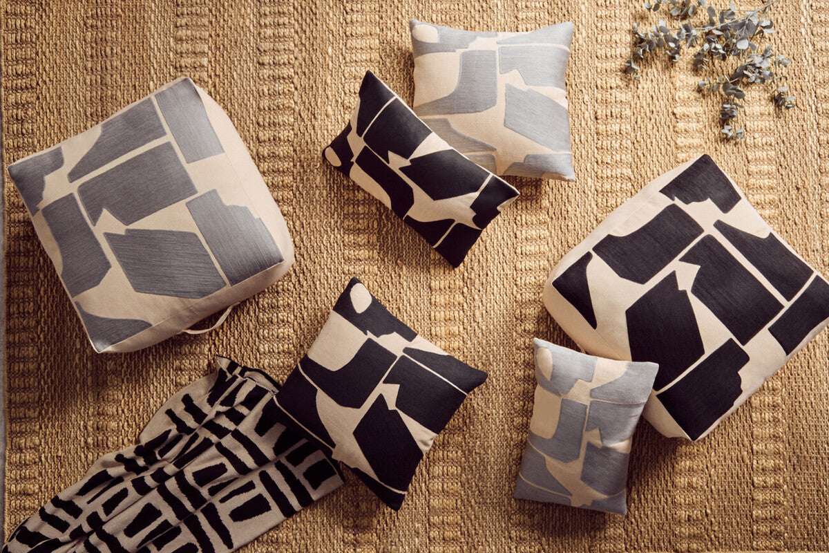 Orsina Black Throw elegantly draped among decorative cushions and poufs showcasing modern patterns