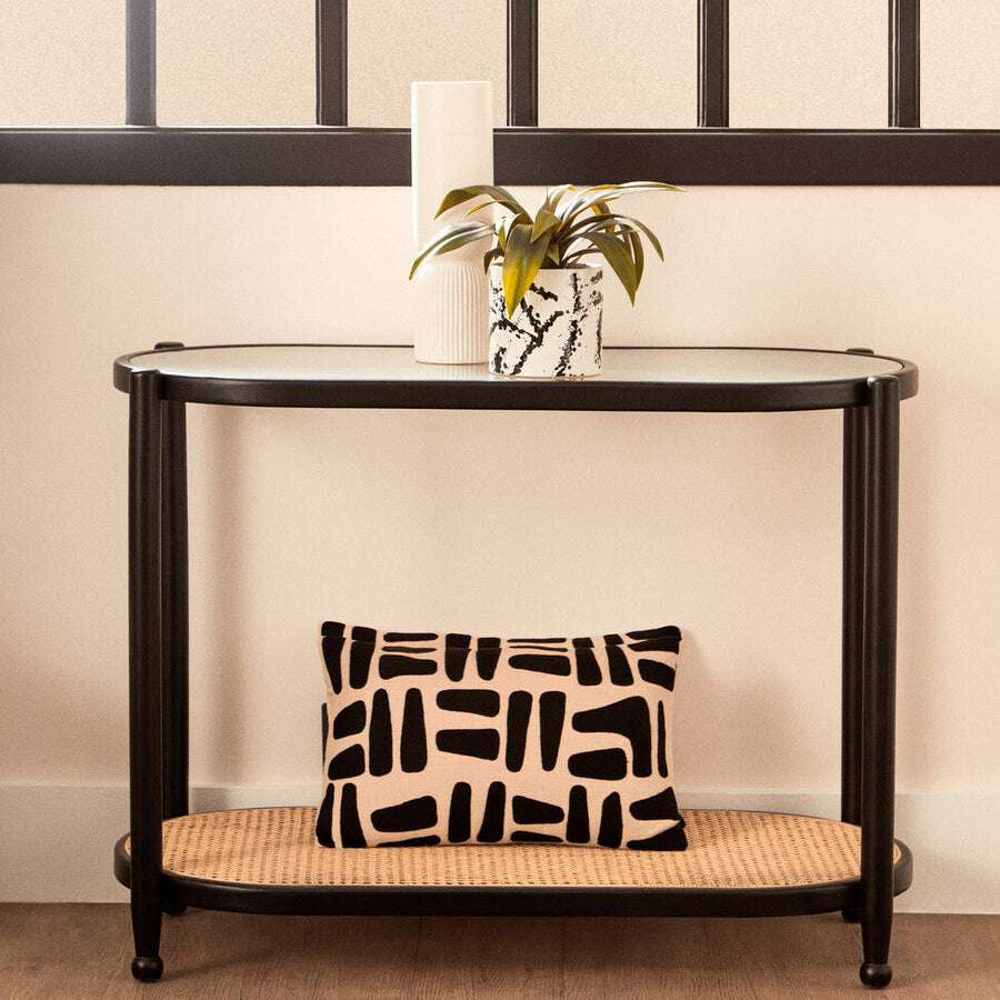 Orsina Console Table in black with a glass top and decorative cushion on the shelf below