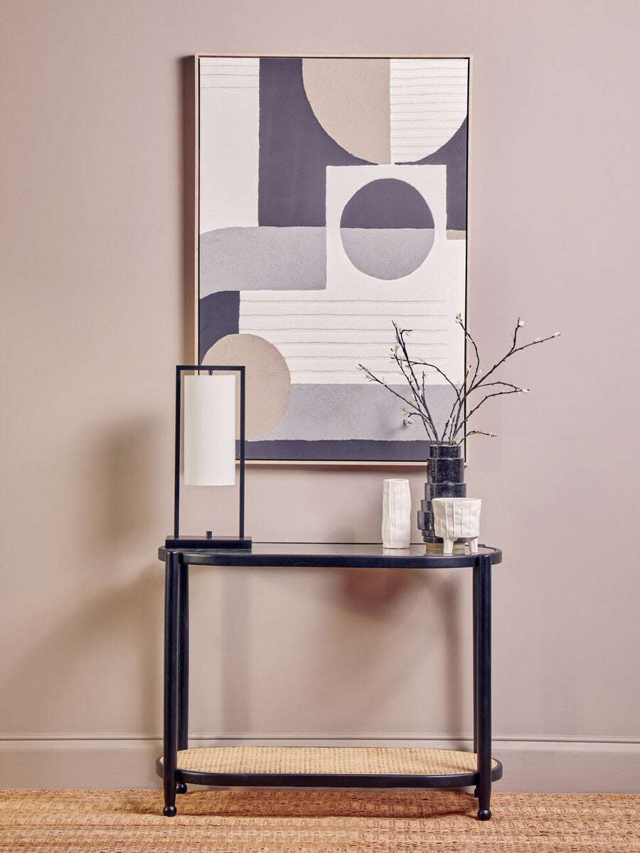 Orsina Console Table with a sleek black design, decorative vase, and modern artwork backdrop