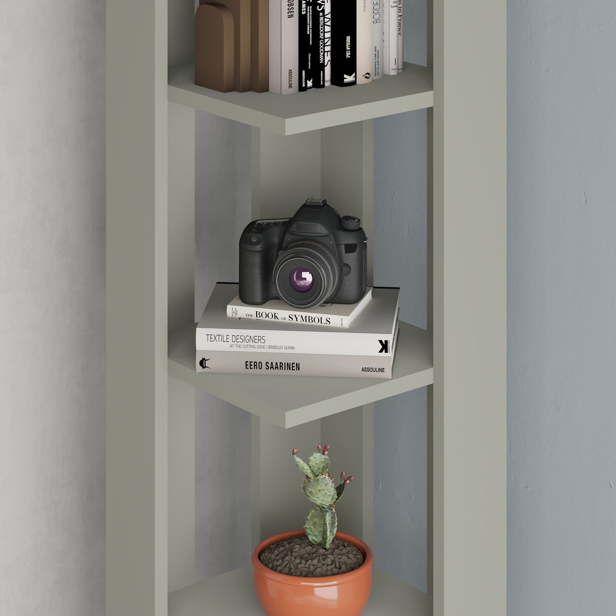 Decortie Corner Bookcase in pastel green with shelves displaying books, a camera, and a potted plant