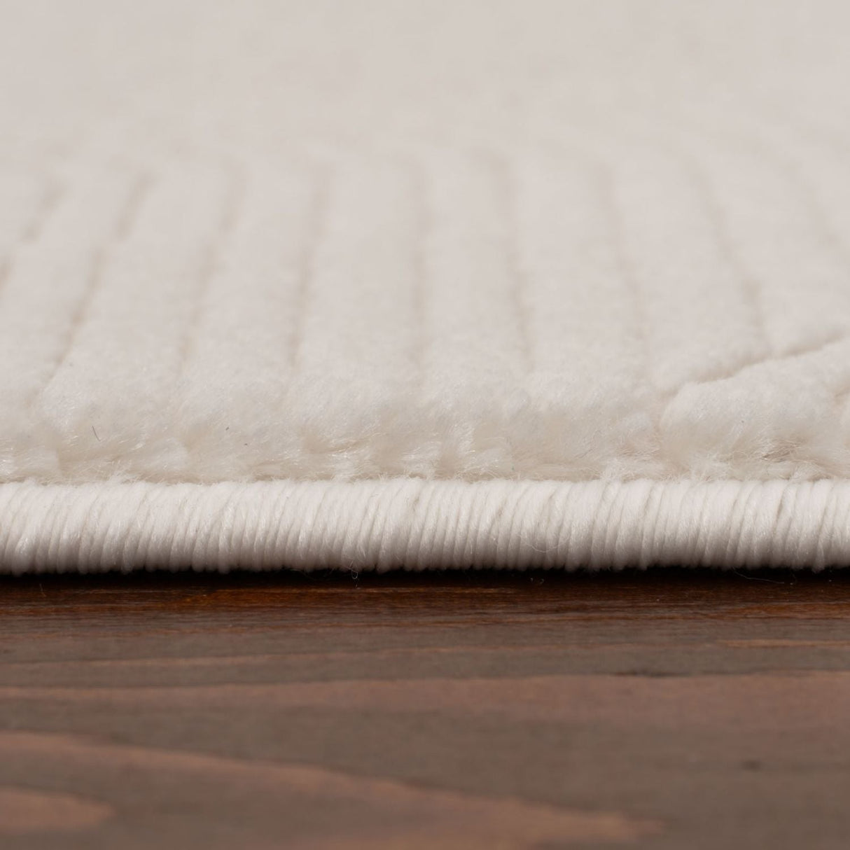Close-up of a soft, textured cream rug with a subtle striped pattern