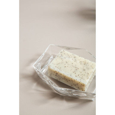 Orsina Soap Dish in clear glass holding a decorated bar of soap on a neutral background