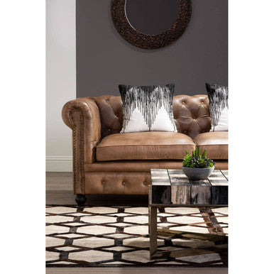 Orsina Embroidered Cushion featuring a stylish design on a leather Chesterfield sofa