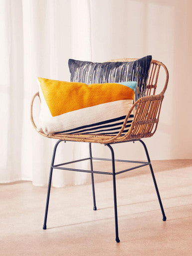 Orsina Embroidered Cushion in vibrant colours placed on a stylish rattan chair