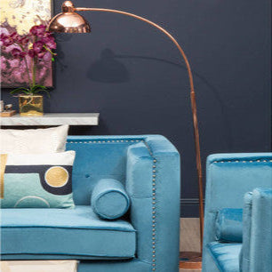 Orsina Arc Floor Lamp with a Copper Shade beside a Stylish Blue Sofa in a Modern Living Room