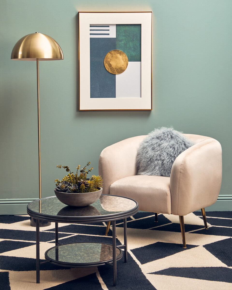 Orsina Floor Lamp in Gold beside a plush armchair and decorative table in stylish living room
