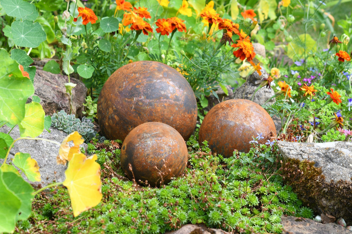 Rustic Garden Metal Balls in Various Sizes Surrounded by Colourful Flowers and Greenery