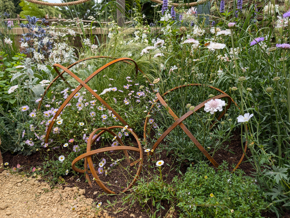 Decorative Garden Sphere Ornaments made of metal, nestled among vibrant flowers in a garden setting