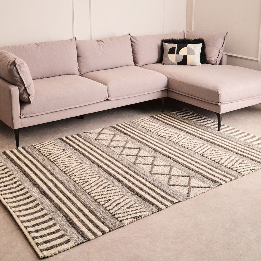 Orsina Geometric Rug in neutral tones placed under a modern sofa in a stylish living room
