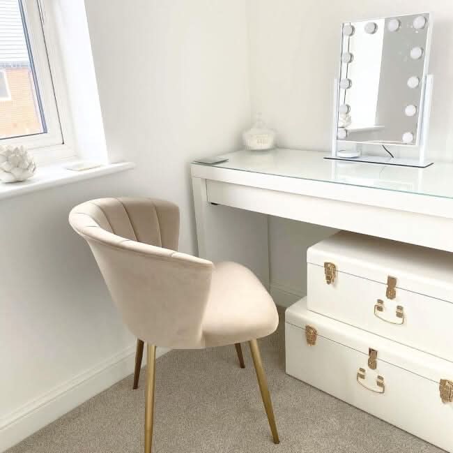 Elegant Hollywood Mirror on a white vanity table complemented by a plush chair and stylish storage boxes