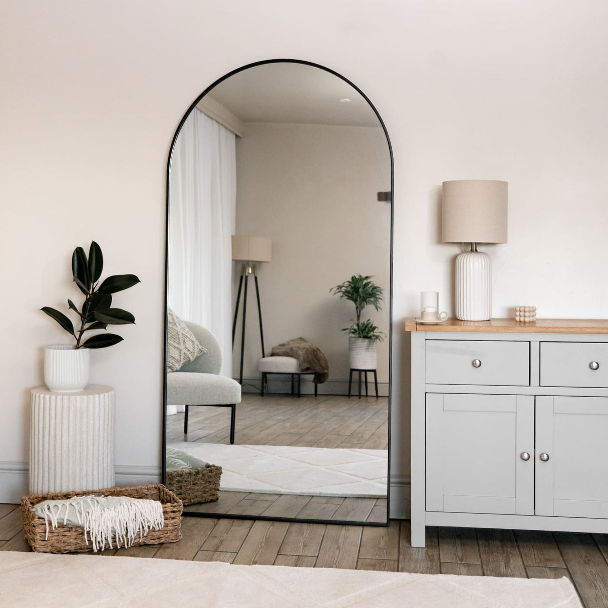 Jobu Home Arched Mirror Leaning Against a Light Wall with Stylish Decor and Plants