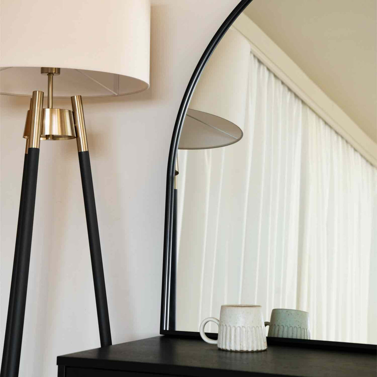 Stylish Jobu Home Arched Mirror above a dark dresser with a lamp and decorative cups