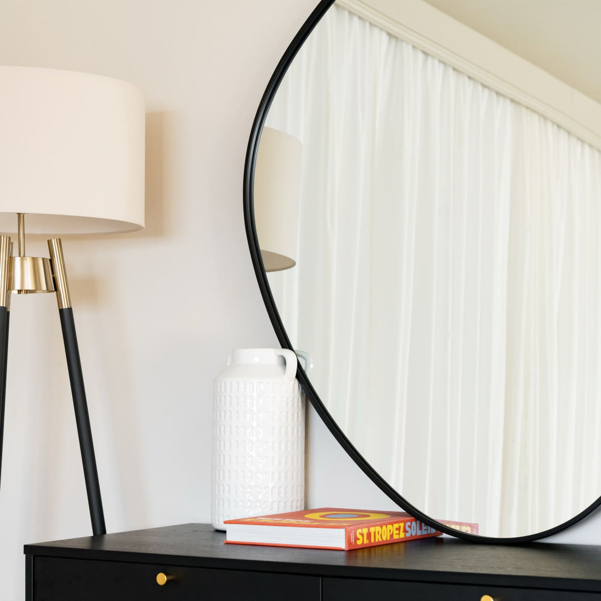 Jobu Home Pebble Mirror in round shape with stylish lamp and decor on a sleek black table
