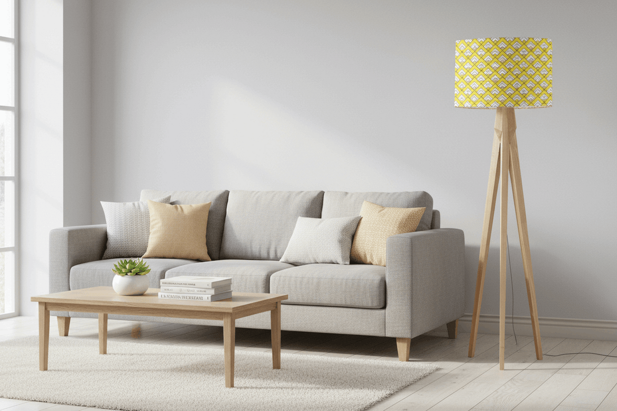Stylish lampshade in yellow geometric pattern on a wooden tripod lamp next to a grey sofa