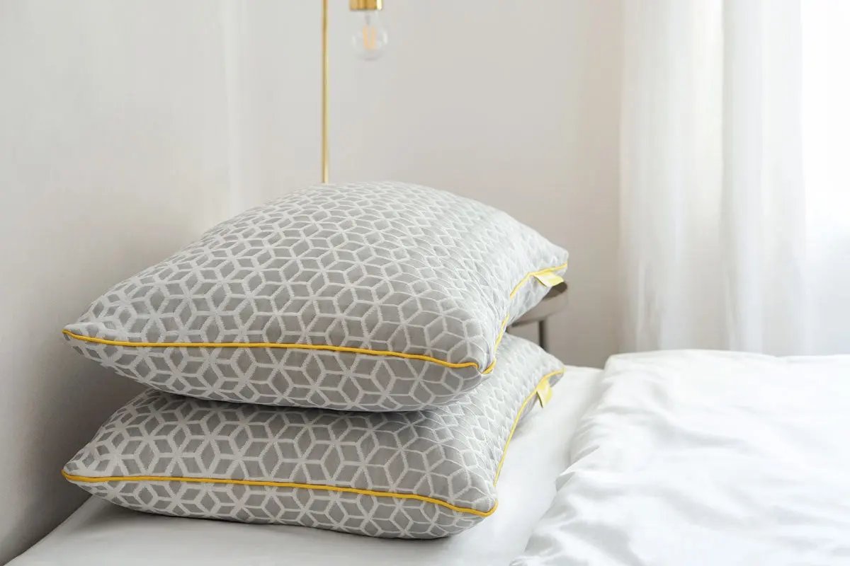 Brightr Sleep adjustable and hypo-allergenic pillow with a stylish grey design and yellow trim, featuring a pillow protector