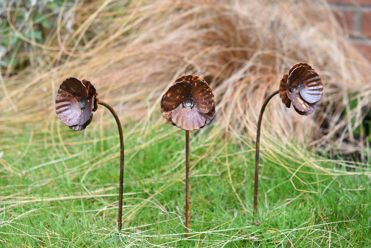 Set of three metal Poppy Flower garden decorations with intricate petal designs on green grass