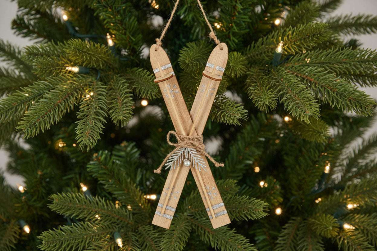 Rustic Crossed Skis Christmas bauble decoration with natural wood finish hanging on a festive tree