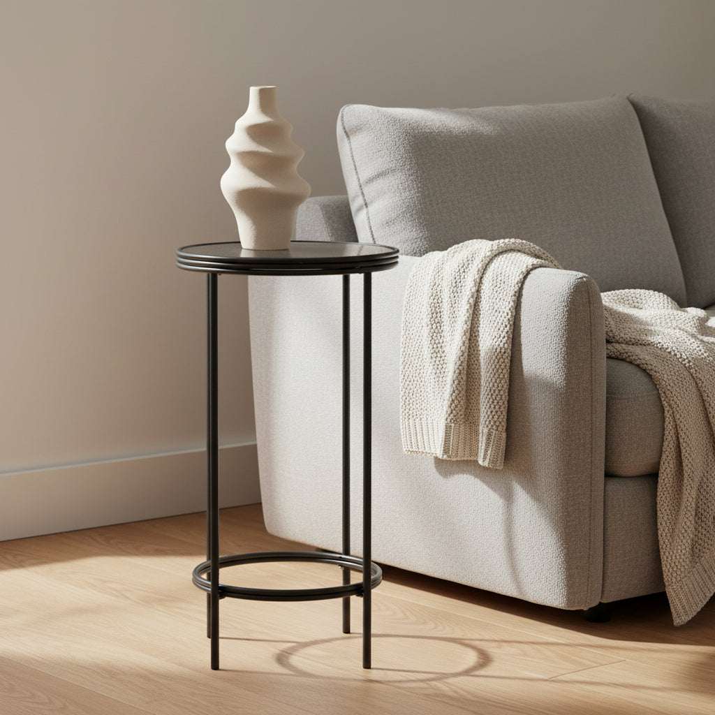 Orsina modern side table in black metal beside a grey couch with cozy knitted throw