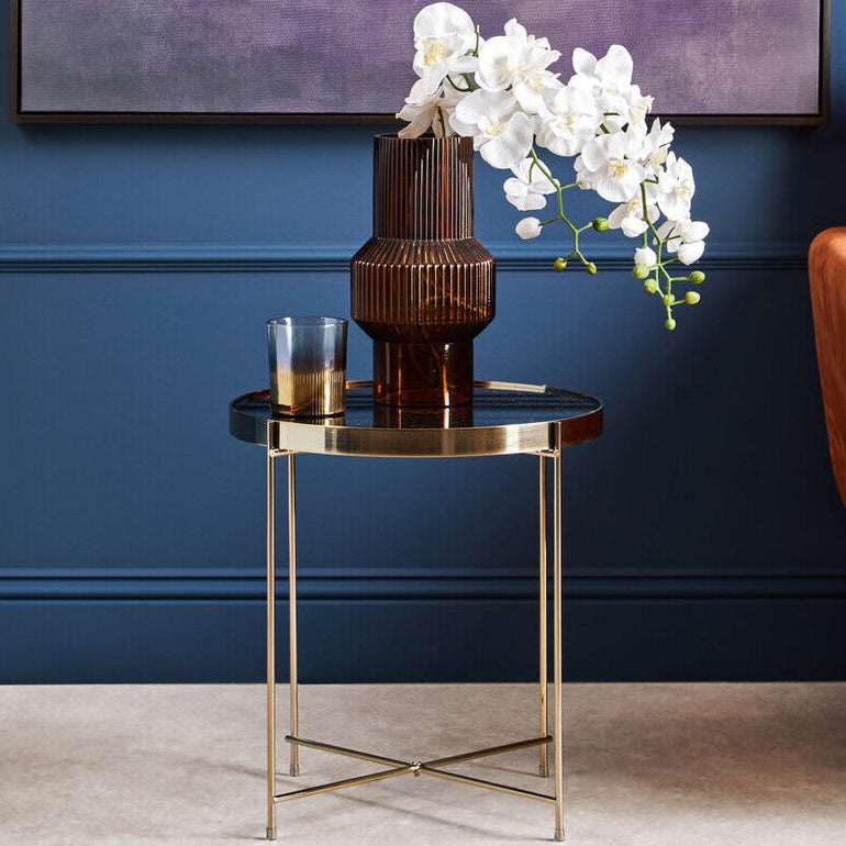 Elegant Orsina Side Table with a sleek black surface and gold legs, styled with a vase and flowers