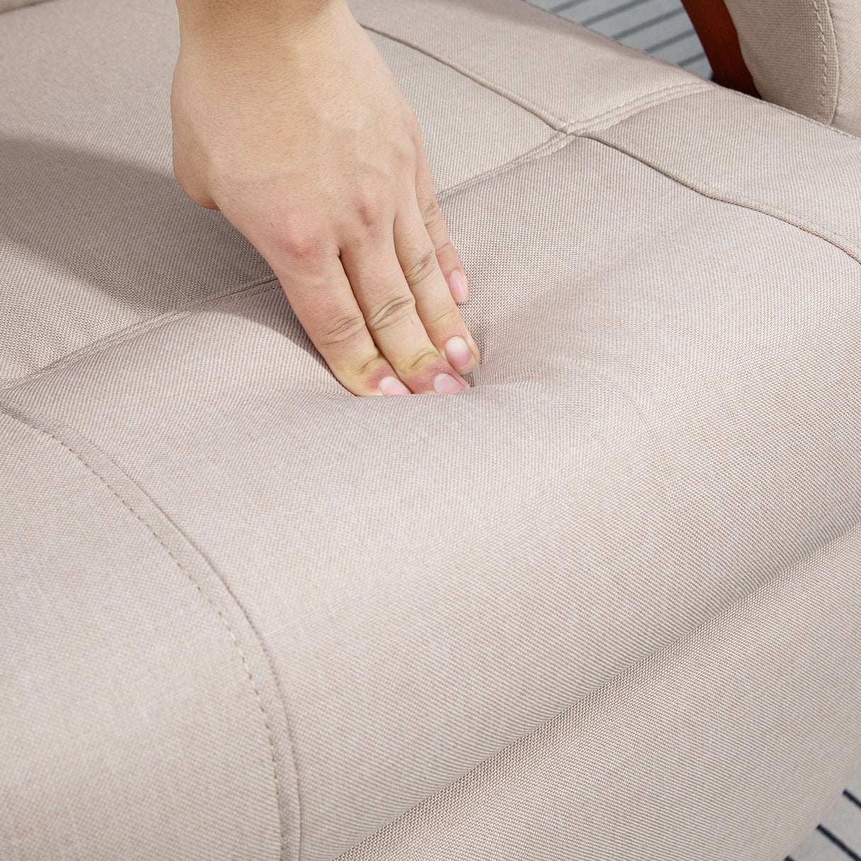 Close-up of a hand pressing the soft upholstery of a Wise Galleria swivel chair in neutral colour