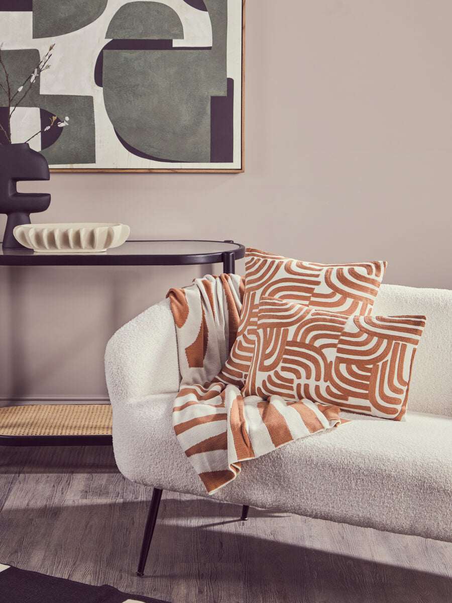 Orsina Terracotta Throw draped over a stylish sofa with patterned cushions