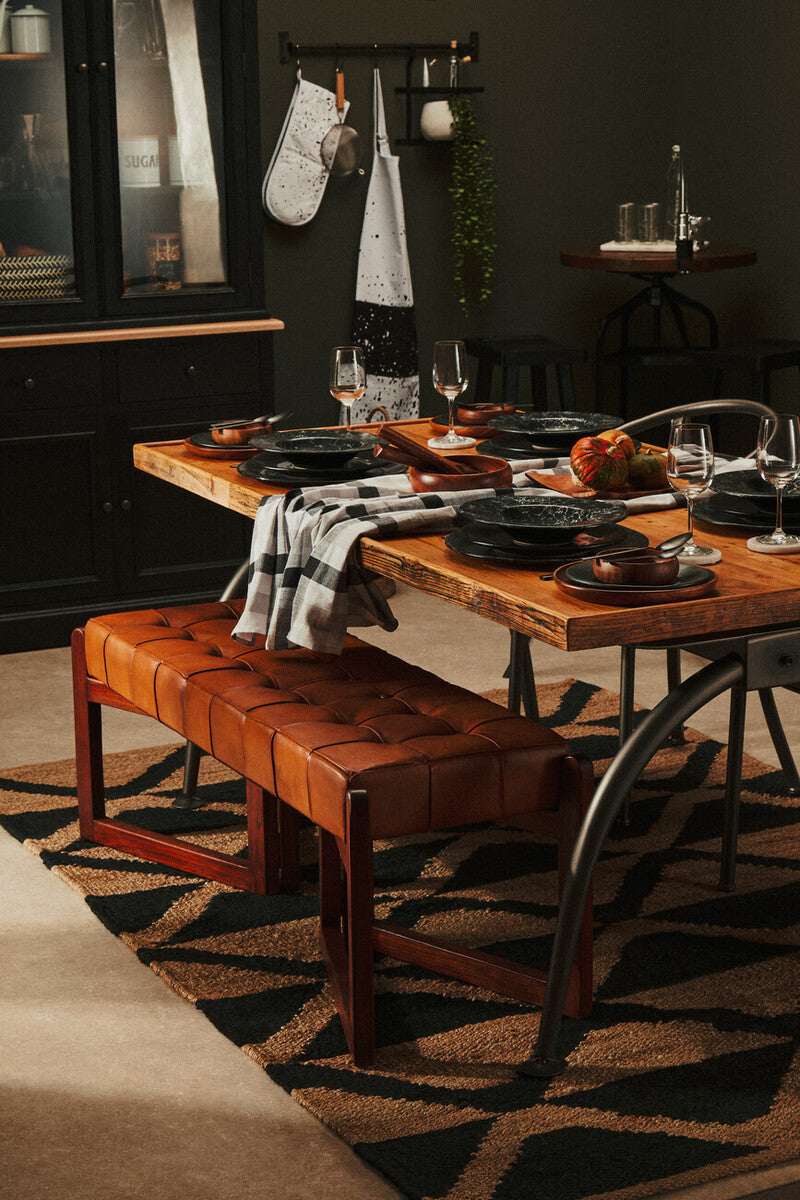 Stylish dining area featuring an Orsina Hemp Rug beneath a wooden table and leather bench