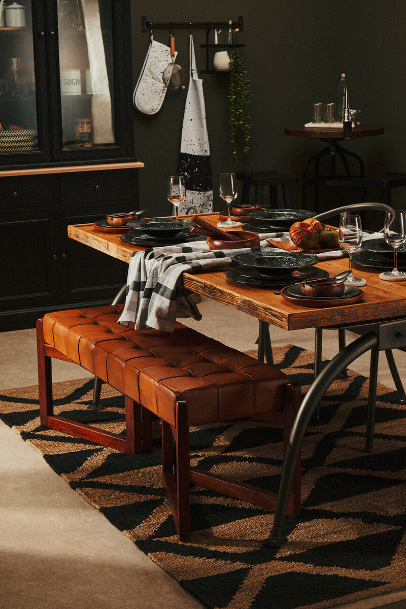 Stylish dining area featuring an Orsina Hemp Rug beneath a wooden table and leather bench