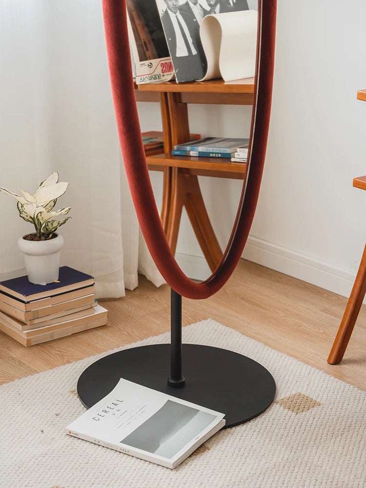 Elegant Nisu Home Wall Mirror with a sleek velvet frame, standing on a black base in a stylish interior