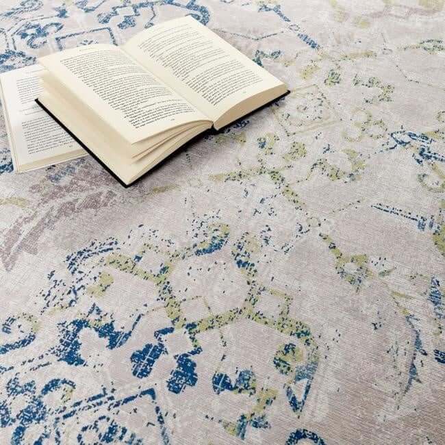 Elegant washable rug in soft shades of blue and green, styled with an open book on top