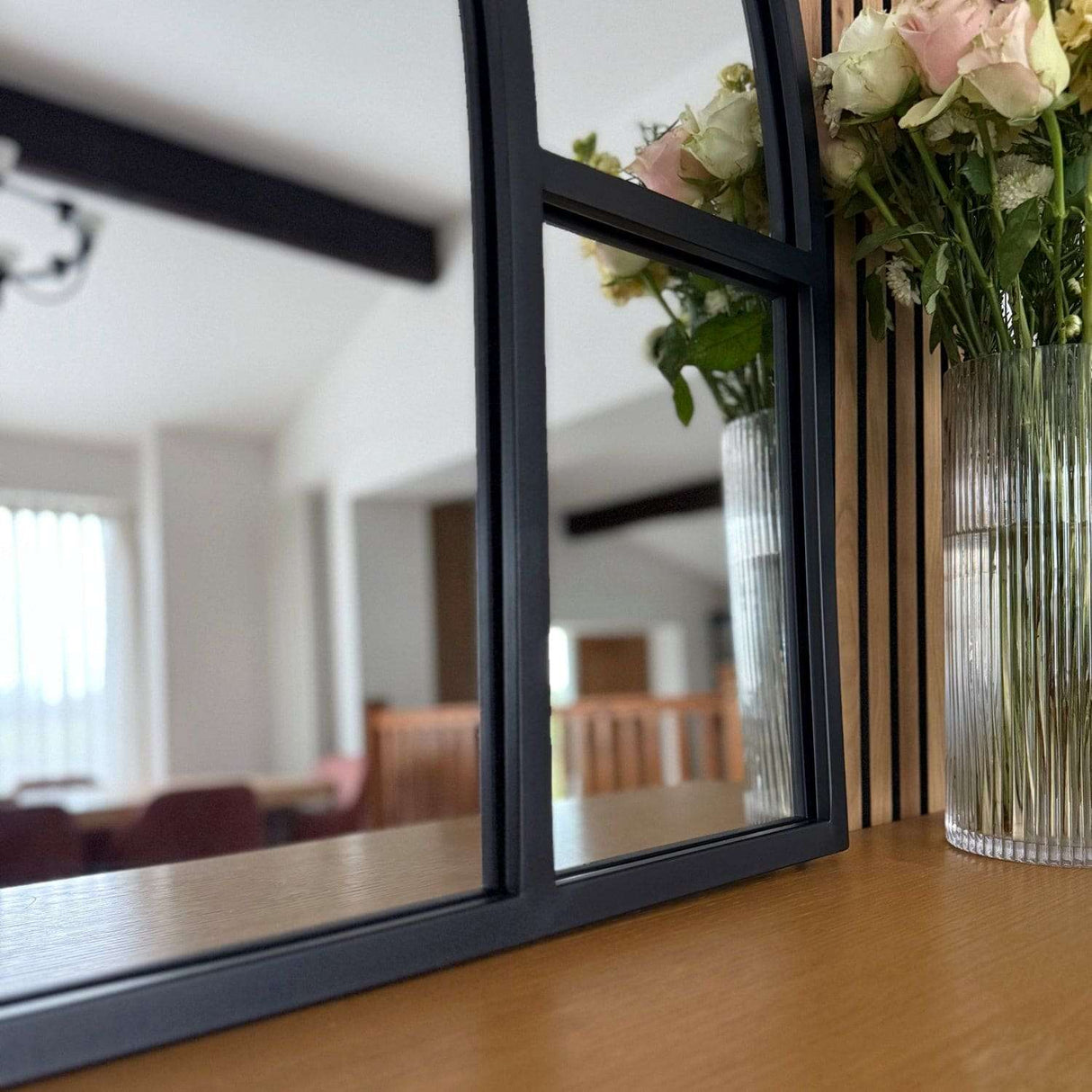Jobu Home Window Mirror with a Black Frame Reflecting a Floral Arrangement on a Wooden Table