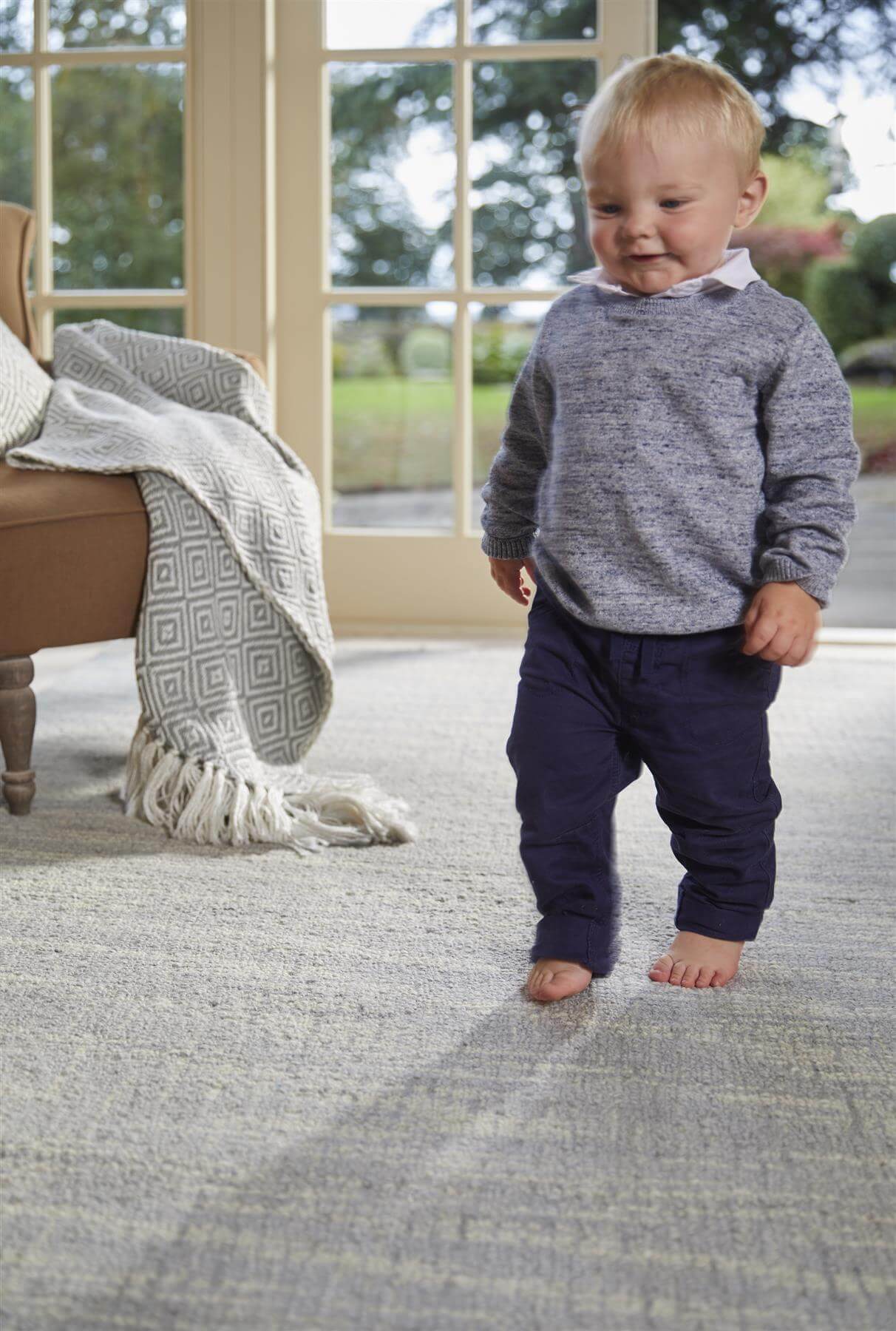 A child walking on a soft grey wool rug in a cozy living room setting