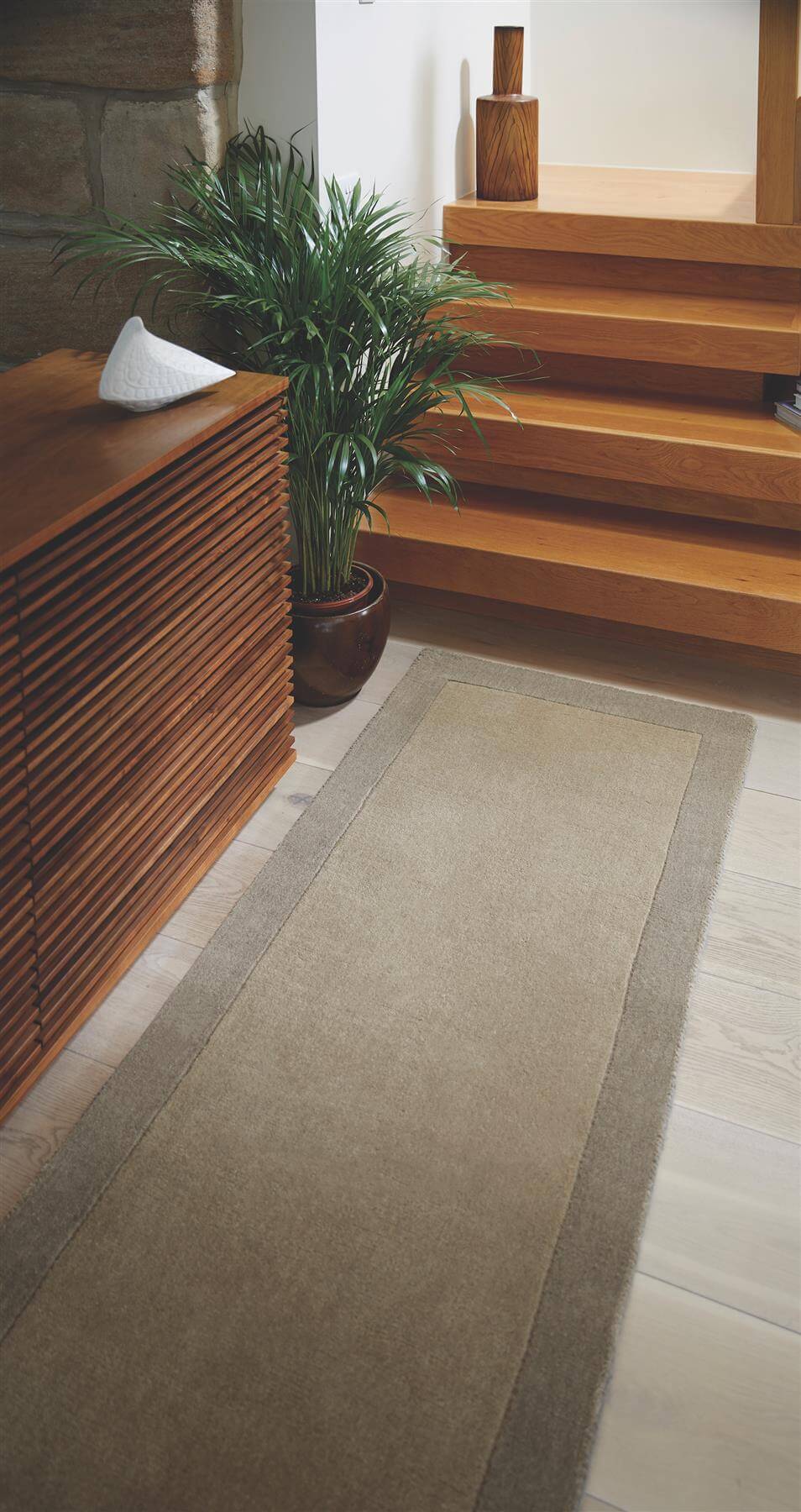 Elegant wool rug in a neutral tone, enhancing a stylish entryway with wooden stairs