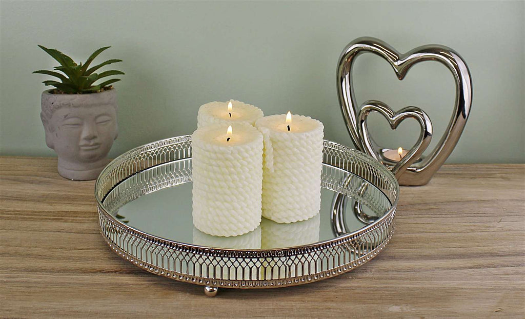 Decorative accessories including textured candles, a mirrored tray, heart-shaped sculptures, and a plant in a face planter