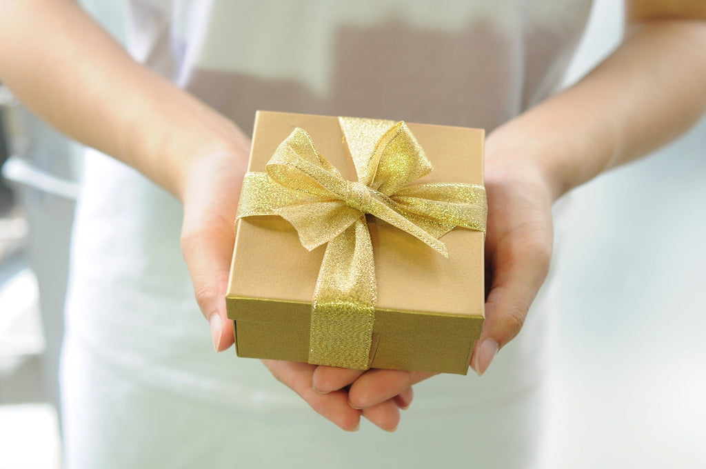 Person holding a gold gift box with golden ribbon perfect for homeware holiday presents