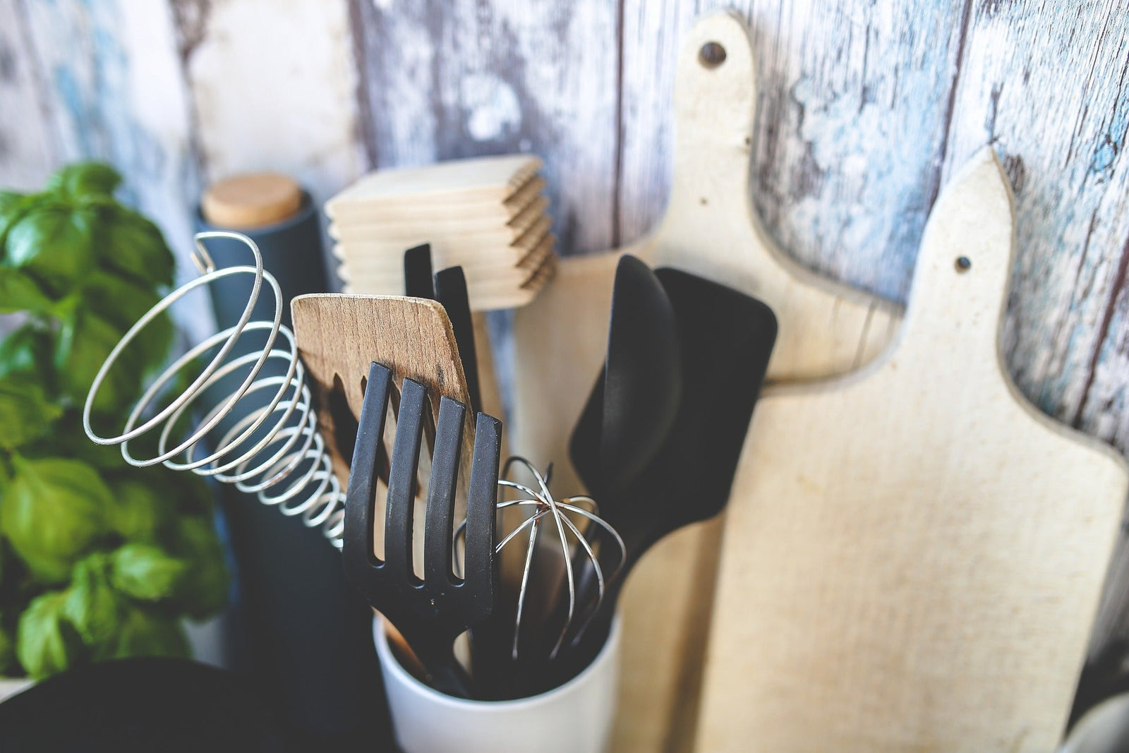 Variety of kitchen accessories including spatulas, whisks, and cutting boards in a stylish kitchen setting