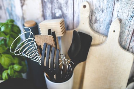Variety of kitchen accessories including spatulas, whisks, and cutting boards in a stylish kitchen setting