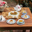 Elegant Afternoon Tea Plates set on a wooden table with tea, cake, and floral decorations