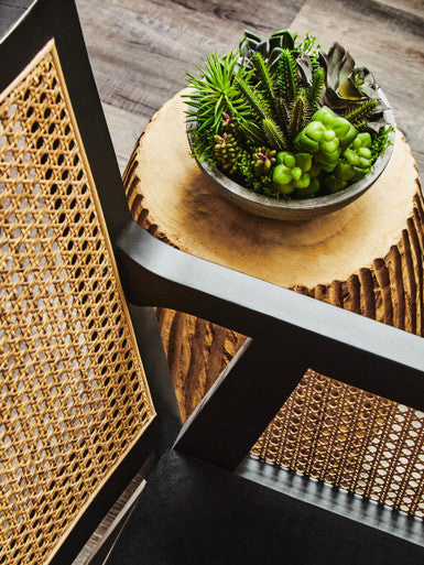 Stylish Orsina Arm Chair with woven rattan detail and decorative plant on a wooden stool