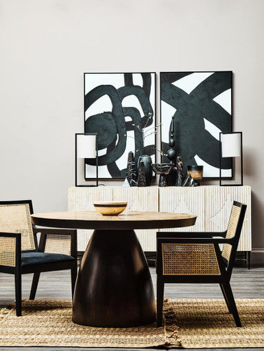 Orsina Arm Chair in rattan style beside a round table and modern art decor