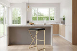 Orsina Bar Stool with a sleek black seat and a stylish gold frame in a modern kitchen setting