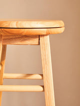 Close-up of Orsina Bar Stool in natural wood finish featuring a smooth seat and sturdy legs