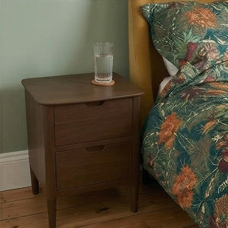 Fishe and Lilly Bedside Table in wood finish with two drawers next to a vibrant floral quilt