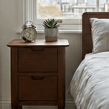 Fishe and Lilly Bedside Table with Two Drawers and a Clock Next to a Plant by the Window