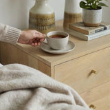 Stylish Fishe and Lilly bedside table with contemporary design, featuring a plant and a cup of tea