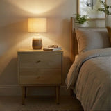 Fishe and Lilly bedside table with two drawers and warm bedside lamp in a softly lit bedroom
