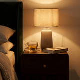 Fishe and Lilly wooden bedside table with a lamp, tea cup, and a book for a cozy bedroom ambiance