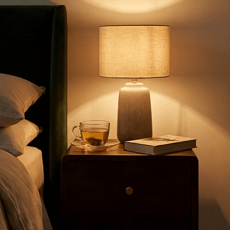 Fishe and Lilly wooden bedside table with a lamp, tea cup, and a book for a cozy bedroom ambiance